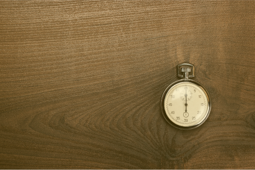 stopwatch-over-brown-wooden-background-