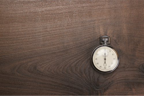 stopwatch-over-brown-wooden-background